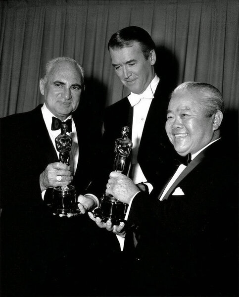 James Stewart, au centre, entre Leon Shamroy et James Wong Howe, à droite, Oscars en mains, en 1964 - L'Oscar de Leon Shamroy lui revient pour son travail en couleur sur <i>Cléopâtre</i>, de Joseph L. Mankiewicz, et celui de James Wong Howe, pour le noir et blanc de <i>Hud</i>