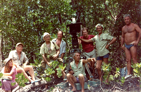 Sur le tournage de "L'Africain" de Philippe de Broca en 1983 - De gauche à droite : Hélène Sébillote, scripte, Jean Penzer, Georges Pierre, photographe de plateau, Yves Agostini, cadreur, Philippe de Broca, assis au pied de la caméra, Michel Coteret, assistant opérateur, Marcel Gellier, chef machiniste, Manu, machiniste