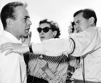 Humphret Bogart, Connie Reeve, maquilleuse, et Ossie Morris sur le tournage de " Plus fort que le diable " de John Huston en 1953 - Photographie tirée de " Out Standing Stills ", livre de photos de plateau édité par nos confrères de la BSC (British Society of Cinematographers)
