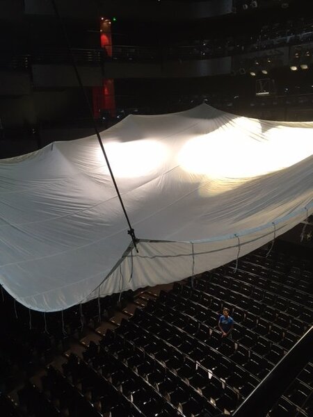 Installation du velum dans la salle de l'Opéra de Lyon - Le décor de l'Opéra avec Philippe Leroy, chef électricien, assis en bas sous le grand velum de 12x12 m tendu la veille du tournage (c'est le plus grand qu'on ait trouvé). <br class='manualbr' />Des découpes et PC de l'Opéra déjà fixés par les électriciens de l'Opéra donnaient l'effet d'éclairage de la salle. <br class='manualbr' />Photo : Ahmed Zaoui