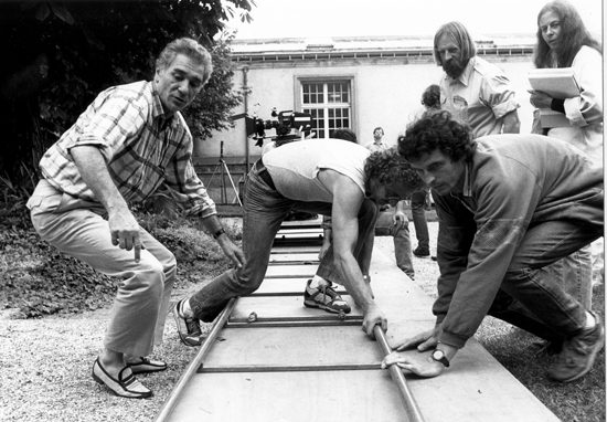 Sur le tournage de "La Chaîne" en 1979 - Claude Faraldo, à gauche, pieds nus dans des mocassins blancs, aidant les frères Dagberg, machinistes, à la pose d'un travelling, sous l'œil d'Anne Mirmant, scripte, et de Christian Garnier, cadreur