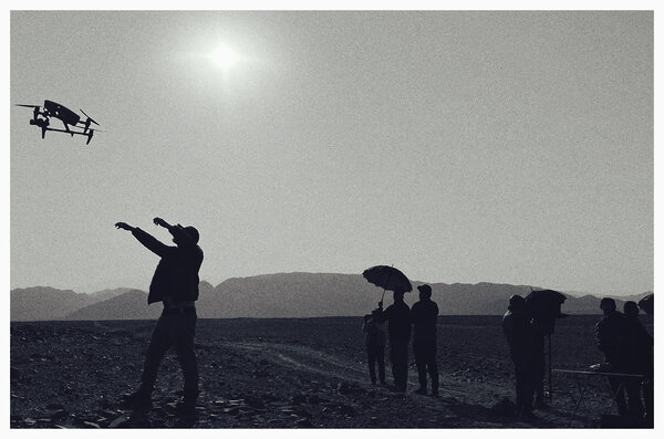 September 7, 2024 | Photo by Gilles Porte (iPhone) - Three drones stare at me like three cyclops in the middle of the desert, while the sun is slow to rise above a hill, delaying my forecast by 20 minutes: an Inspire 3, an Inspire 2 and another, smaller drone. Now that's a luxury I've not been very accustomed to on this shoot! The answer to my question is not long in coming: the small drone won't film, but it will help us spot our targets and save us flight time for the other two drones, given the low number of batteries we have!<br class='manualbr' />On the first flight, I get out my stopwatch. The result is clear: 3 sets of batteries last between 10 and 15 minutes each for the Inspire 3... 5 sets of batteries last 15 minutes each with the Inspire 2... We must also account for the fact that it takes 40 minutes' time to recharge a set of batteries with the small red generator that we have brought along with us, so long as other batteries are not being recharged at the same time... That would be too easy!<br class='manualbr' />To top it all off, I discover that the Inspire 2 has a 400-meter range, after which we lose connection. Even though Alberto (the archaeologist) gave us a free pass to get as close as possible to the figures, some of them can only be filmed by the Inspire 3, such as “the fisherman”, my favorite one!<br class='manualbr' />And to think I had thought for a moment that this last shoot was going to be like a vacation!