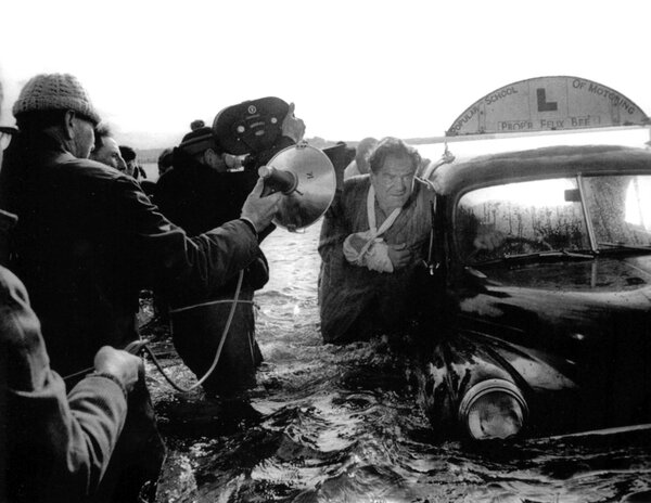 Gilber Taylor tenant un éclairage portatif sur le tournage de "Cul-de-sac", de Roman Polanski, en 1966 - DR