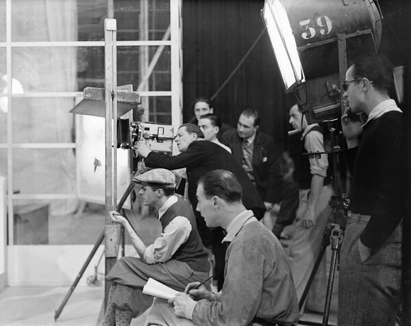 Tournage de "A nous la liberté" - René Clair, casquette sur la tête, Georges Raulet (selon toute vraisemblance), à l'œilleton du Caméréclair, et Georges Périnal, manches retroussées et pantalon clair